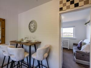 a dining room with a table and chairs and a clock at Sunrise Cottage in Berwick-Upon-Tweed