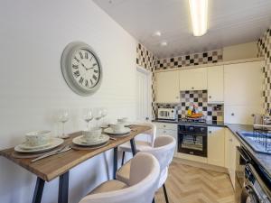 a kitchen with a table with chairs and a clock on the wall at Sunrise Cottage in Berwick-Upon-Tweed