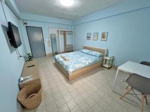 a bedroom with a bed and a desk and a tv at KPP Mansion in Amphoe Phra Khanong