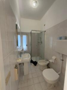 a white bathroom with a toilet and a sink at Hotel Nettuno in Diano Marina +55 photos