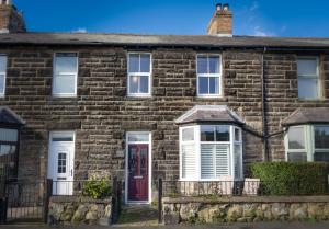 an old brick house with a red door at Northern Hideaways, Darling Cottage in Seahouses