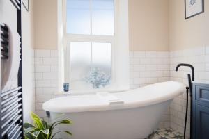 a white bathroom with a tub and a window at Northern Hideaways, Darling Cottage in Seahouses