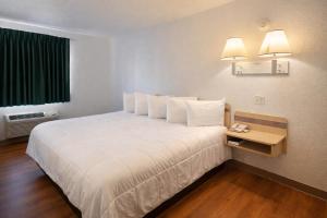a hotel room with a large bed with white sheets at Big Springs Inn in Big Springs