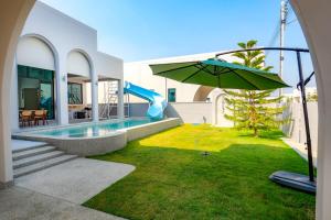 a pool with a slide and an umbrella in a yard at Hello Teepak A34 in Ban Bo Prakhon