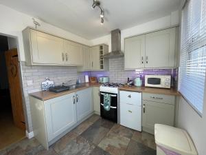 a kitchen with white cabinets and a stove top oven at Trout Cottage in Filey