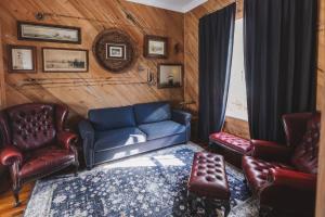a living room with a blue couch and leather chairs at The Gilded Lady - The Cypress Suite in Pensacola +24 photos