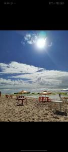 a group of tables and umbrellas on a beach at Suítes estrela dalva in Lauro de Freitas