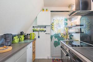 a kitchen with white cabinets and green tiles on the wall at Chalet 53 in Deal