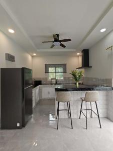 a kitchen with a black refrigerator and two bar stools at jessi house pool in Ban Nok