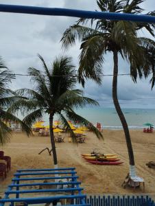 a beach with palm trees and surfboards on it at Pousada Pé no Mar in Japaratinga
