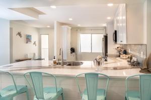 a kitchen with three chairs and a counter with a sink at Lighthouse Point 222 in Sanibel