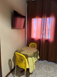 a room with a table and two yellow chairs at Suítes estrela dalva in Lauro de Freitas +4 photos