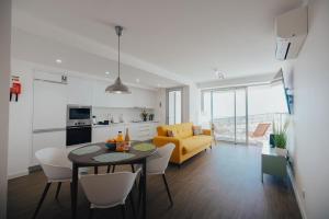 a living room with a table and a yellow couch at Atlantic Residence Pool & Ocean View in Câmara de Lobos