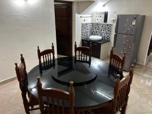 a dining room table with chairs and a refrigerator at Metro Bliz Alua by thestaypoint in Alwaye