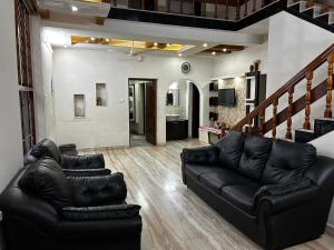 a living room with black leather furniture and a staircase at Metro Bliz Alua by thestaypoint in Alwaye