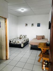 two beds in a room with white tiled floors at LA CASONA SV Hostal in La Libertad +89 photos
