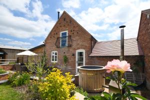 a brick house with a flower garden in front of it at Rowley Farm Holidays in Worcester
