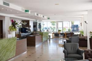 a lobby with chairs and tables in a building at Hotel Regina Fronte Mare in Rimini