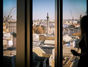 a woman looking out a window at a city at The Londoner in London