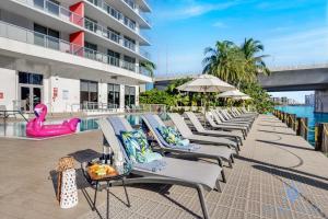 a row of chaise lounge chairs next to a pool at Beachwalk Condo in Hallandale Beach