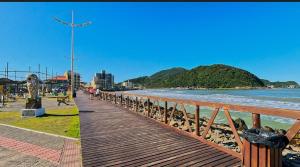 a wooden walkway next to a beach with the ocean at Quarto em residência familiar in Navegantes