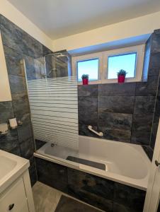 a bathroom with a tub and a sink and two windows at Stadtnah an der Förde S1 in Flensburg