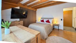 a bedroom with a bed and a flat screen tv at PlanB Stay in Samedan