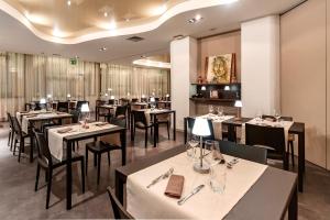 a restaurant with white tables and black chairs at El Patio Hotel in Corciano