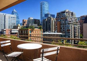 a table and chairs on a balcony with a city skyline at Apartamentos Costanera Centre in Santiago