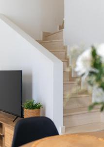 a room with a table and a tv and stairs at Olea White in Skiathos