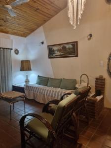 a bedroom with a bed and a couch and chairs at Casa Paso in Paso de la Patria