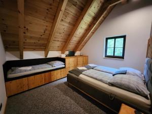 two beds in a room with wooden ceilings at Roubenka Panské Pole in Panské Pole