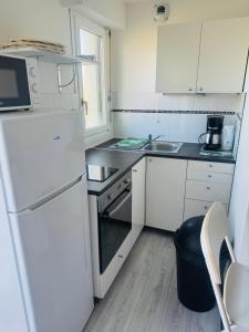 a small kitchen with white cabinets and a white refrigerator at Studio, sea side in Berck-sur-Mer +30 photos