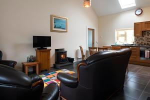 a living room with black leather chairs and a television at Nancy's Seaside Cottage, Renvyle in Renvyle +7 photos