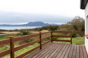 a wooden deck with a view of the water at Nancy's Seaside Cottage, Renvyle in Renvyle
