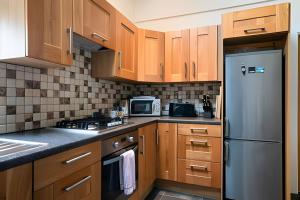 a kitchen with wooden cabinets and a stainless steel refrigerator at Nancy's Seaside Cottage, Renvyle in Renvyle