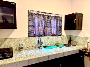 a kitchen counter with a window with purple curtains at The horezt in Kamburugamuwa +1 photo