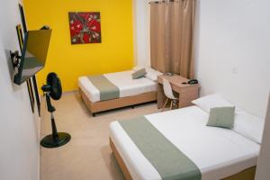 a bedroom with two beds and a desk with a lamp at HOTEL CATALUÑA PEREIRa in Pereira +56 photos