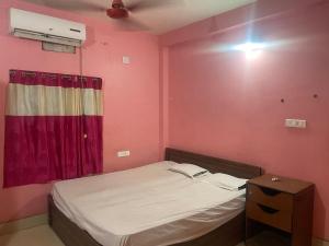 a small bedroom with a bed and a red wall at Care Guest House in Bhubaneshwar