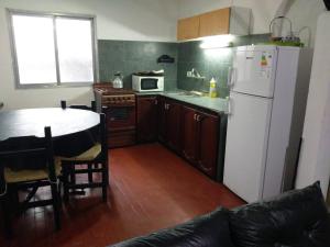 a kitchen with a table and a white refrigerator at Casa La micelia in Pinamar