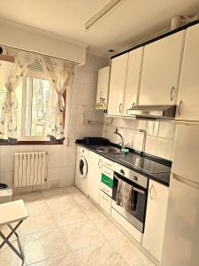 a white kitchen with a sink and a dishwasher at Parque da Ponte in Ourense