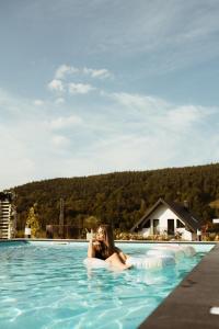 a woman laying on an inflatable pool in the water at Bieszczadzka Wataha in Paszowa