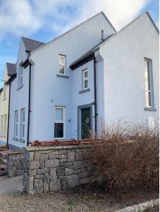 a white house with a stone wall at Clare Cottage in Doolin