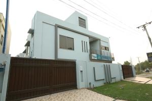 a white house with a brown fence at Cuzzy Inn Stay in Lahore