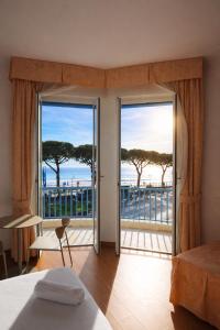 a bedroom with doors to a balcony with a view of the ocean at LVG Hotel Collection - Majestic in Alassio
