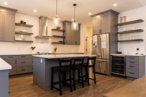 a kitchen with gray cabinets and a island with bar stools at Powder House Chalet by Fernie Central Reservations in Fernie