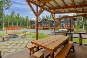 an outdoor patio with a wooden table and a grill at Studio Steps to Kenai River w/ Fire Pit! in Sterling