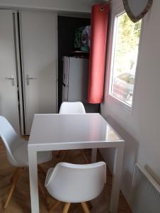 a white table and two white chairs in a room at Location mobil home in Litteau +4 photos