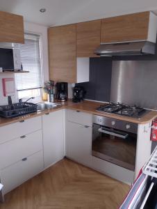 a kitchen with white cabinets and a stove top oven at Location mobil home in Litteau
