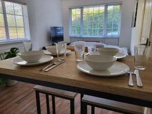 a wooden table with plates and bowls and glasses on it at Little Brookfield in Lymington